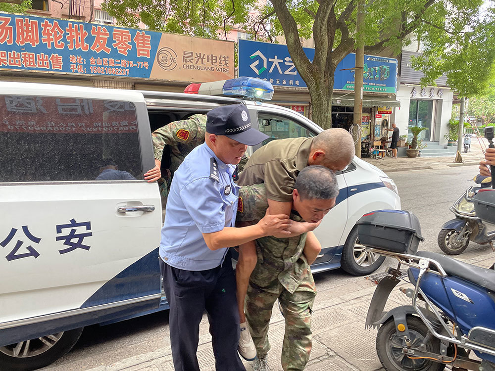 一位年过半百的老伯因脑梗而不能自主站立，民警将他背上警车转移至附近的酒店。澎湃新闻记者 徐祯曜 图